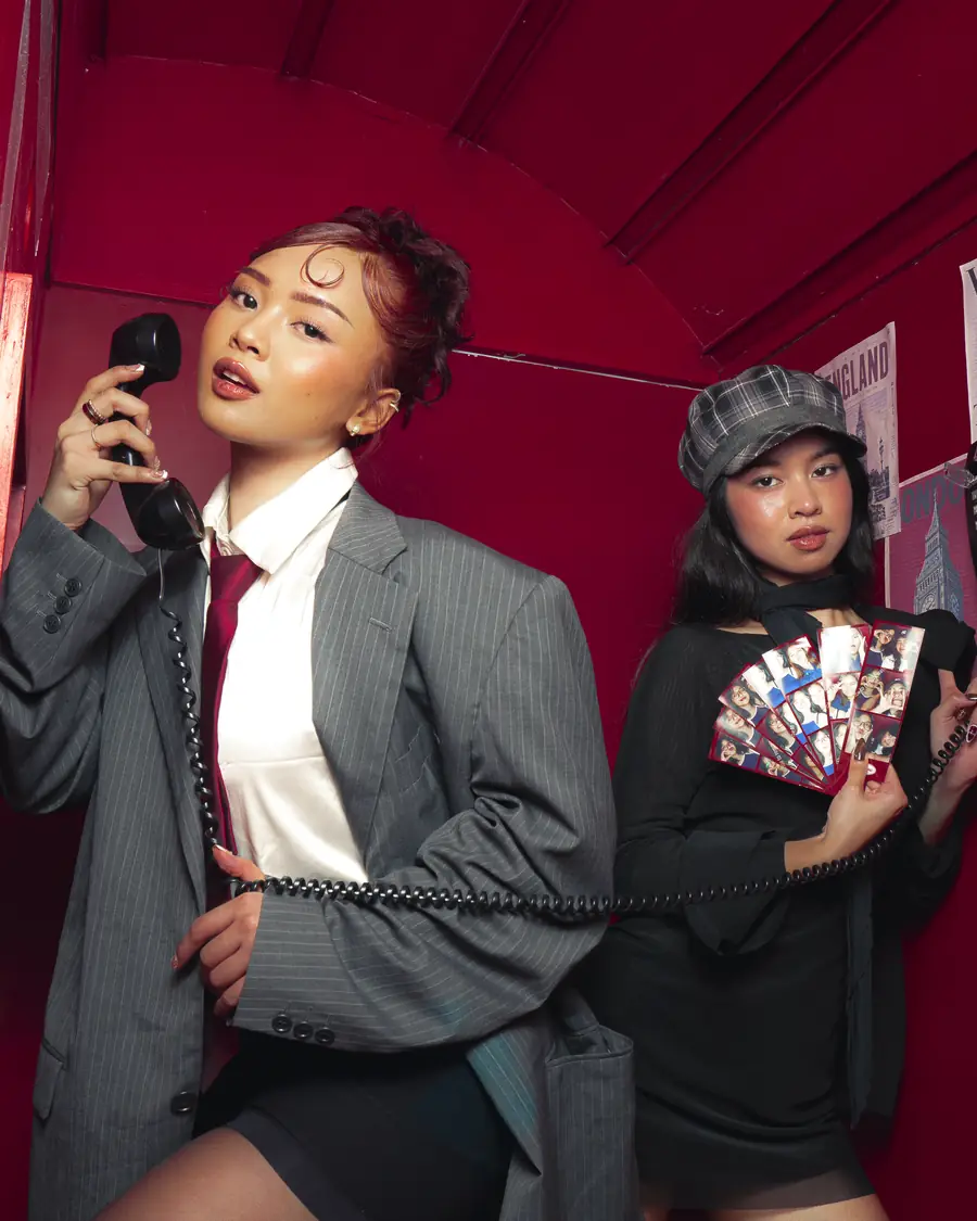 Two guests inside the red booth, one on the phone, one holding photo strips under a Union Jack