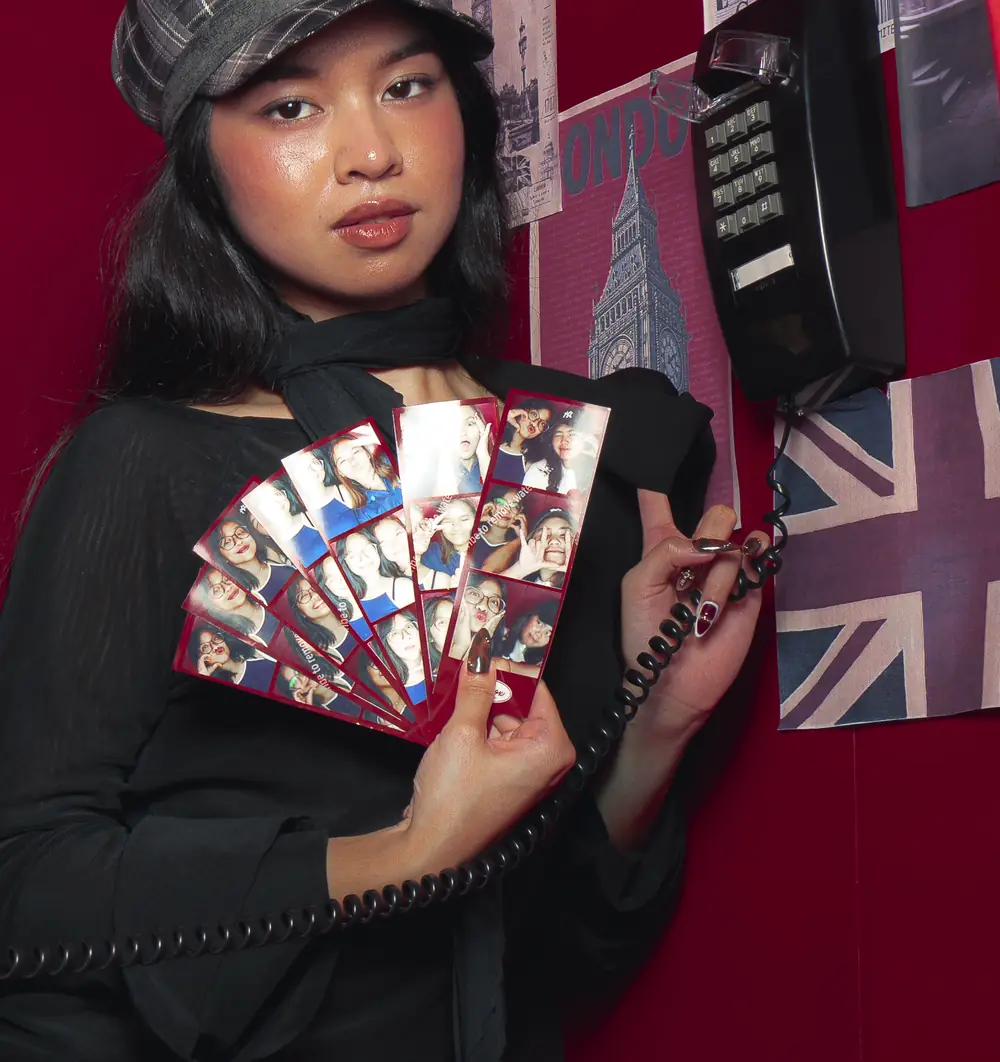 A guest inside the booth fanning out a handful of Dialbox photo strips