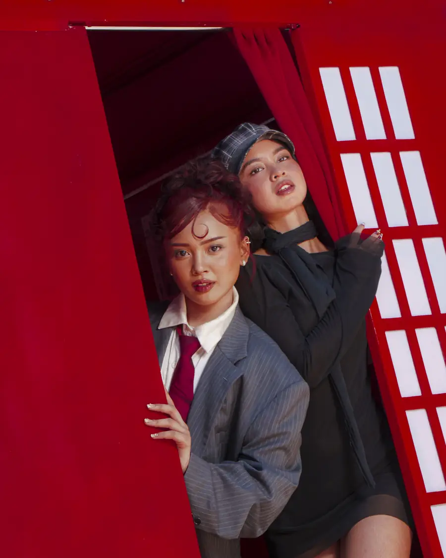Two friends leaning out of the booth doorway