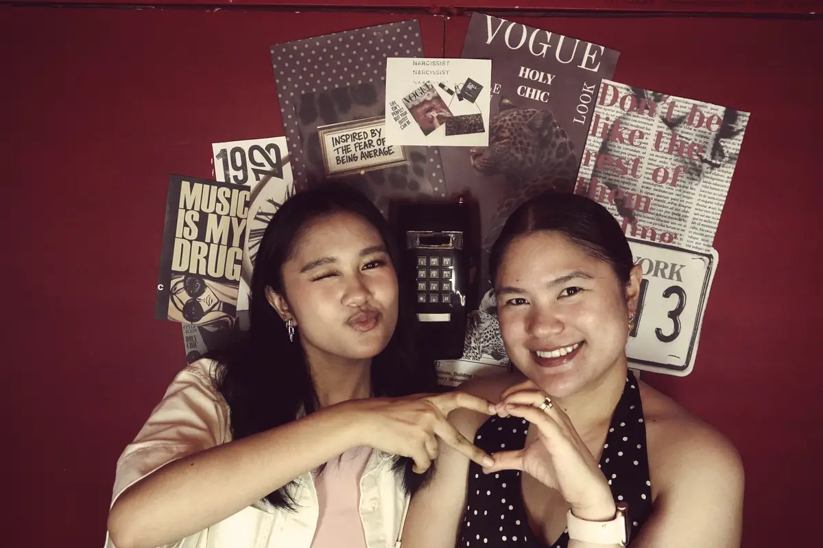 Two friends making a heart inside the booth at Pug Street