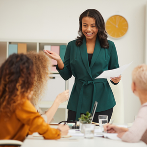 Professional woman confidently expressing herself in team meeting, relaxed posture, genuine interaction,