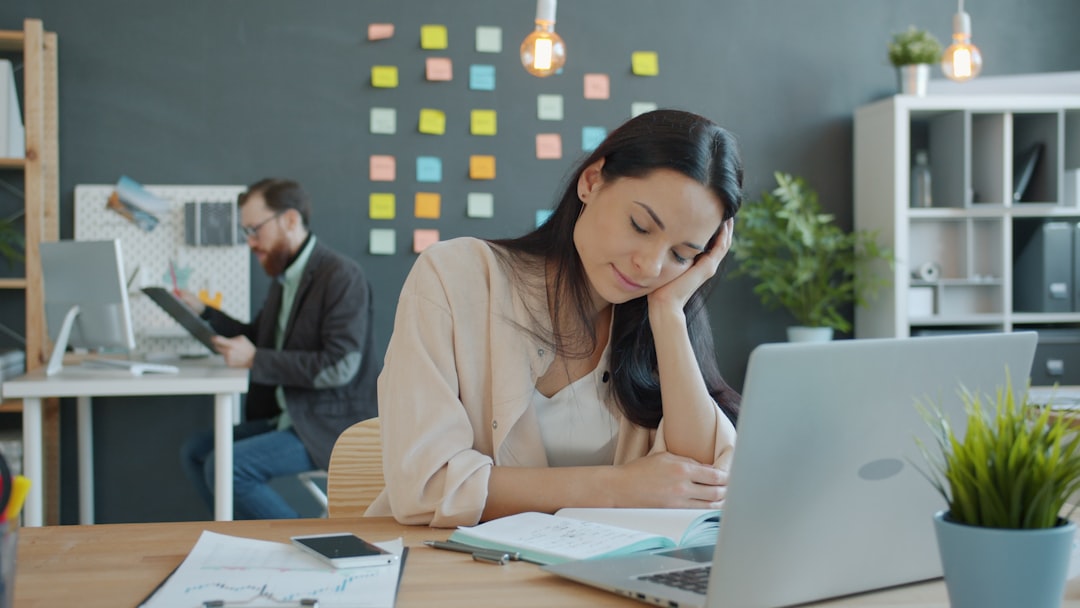 Business owner sitting at a desk late at night, looking exhausted while surrounded by work.