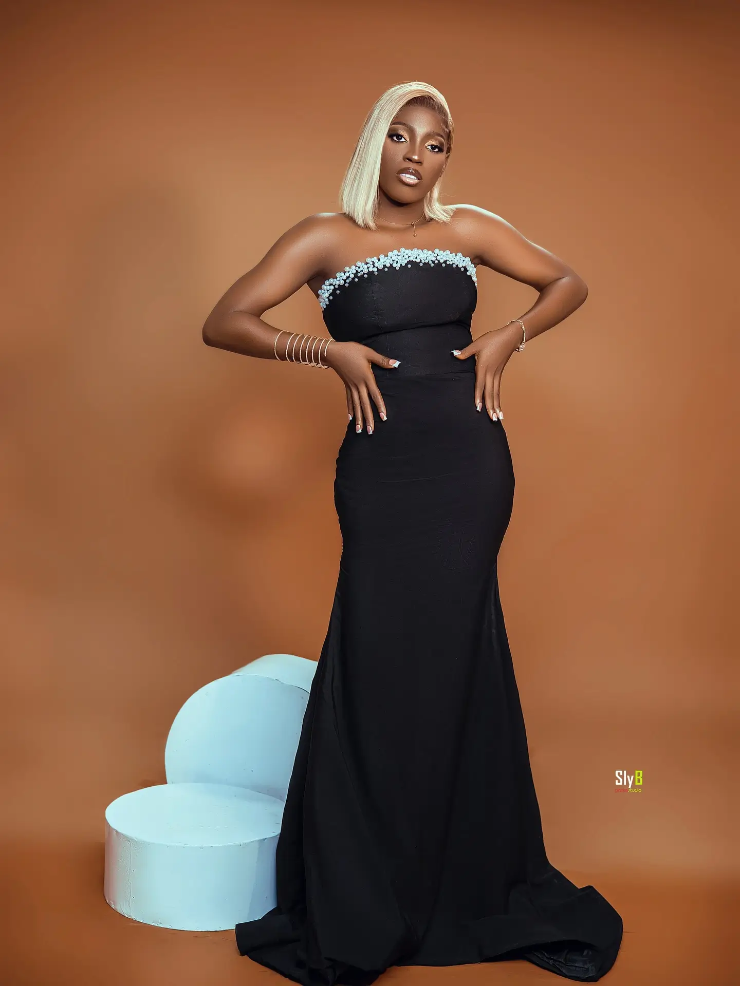 Woman in a black strapless gown standing with her hands on her hips.