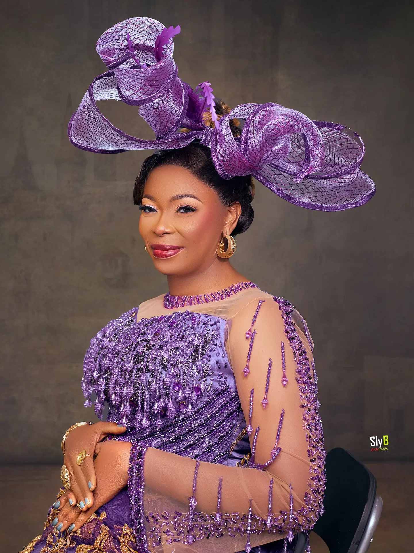 Close-up portrait of a woman wearing an elaborate purple headpiece and beaded traditional dress.