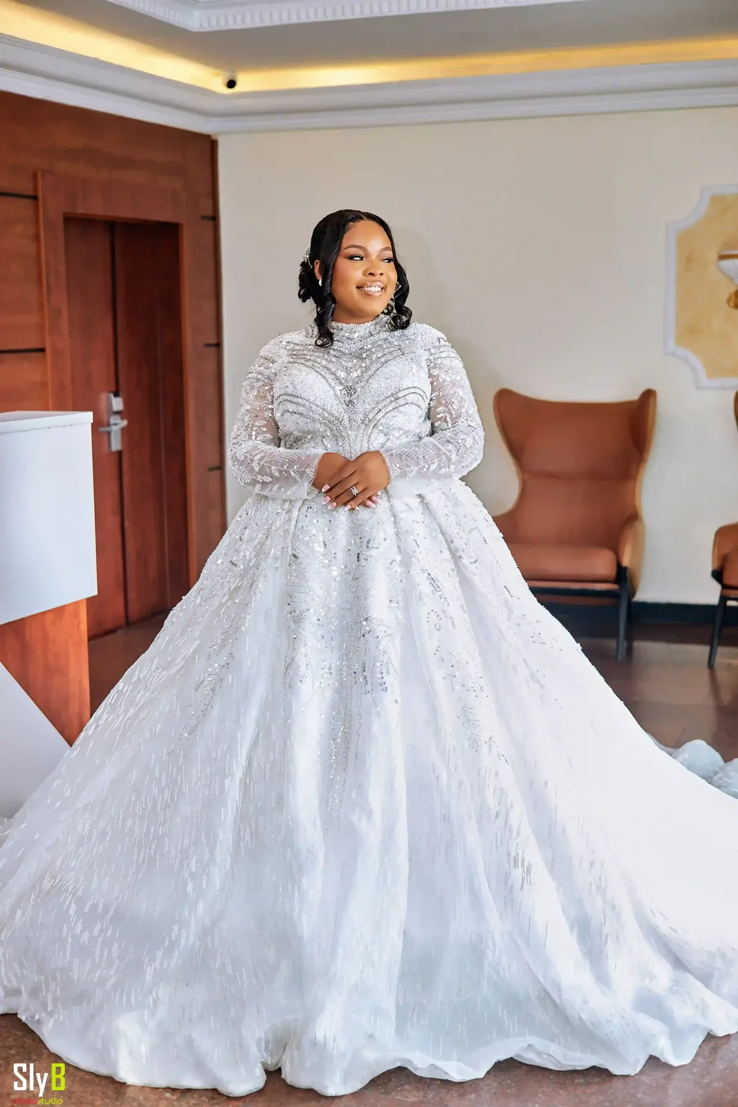 Bride standing indoors in a detailed white lace wedding gown