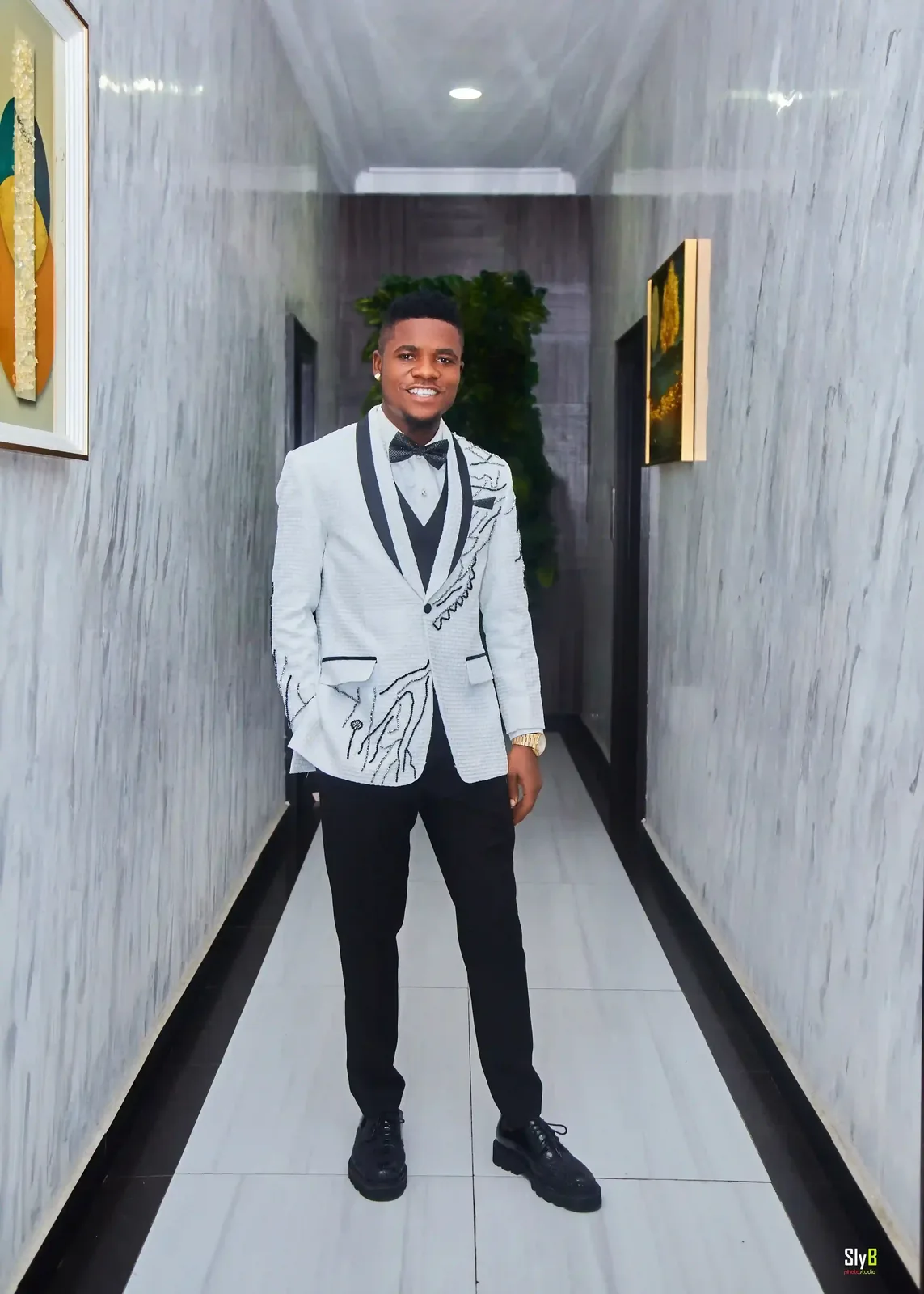 Man standing in a hallway wearing a silver formal jacket