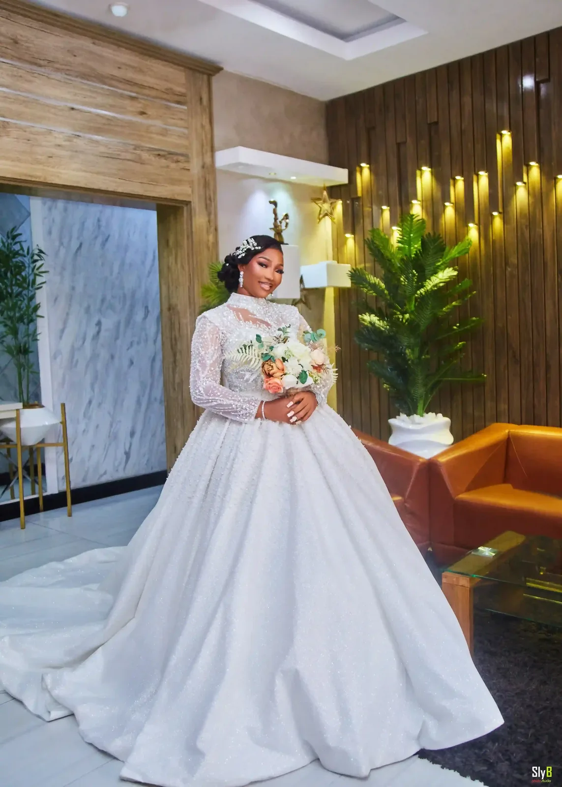 Bride standing indoors in a white wedding gown with flowers