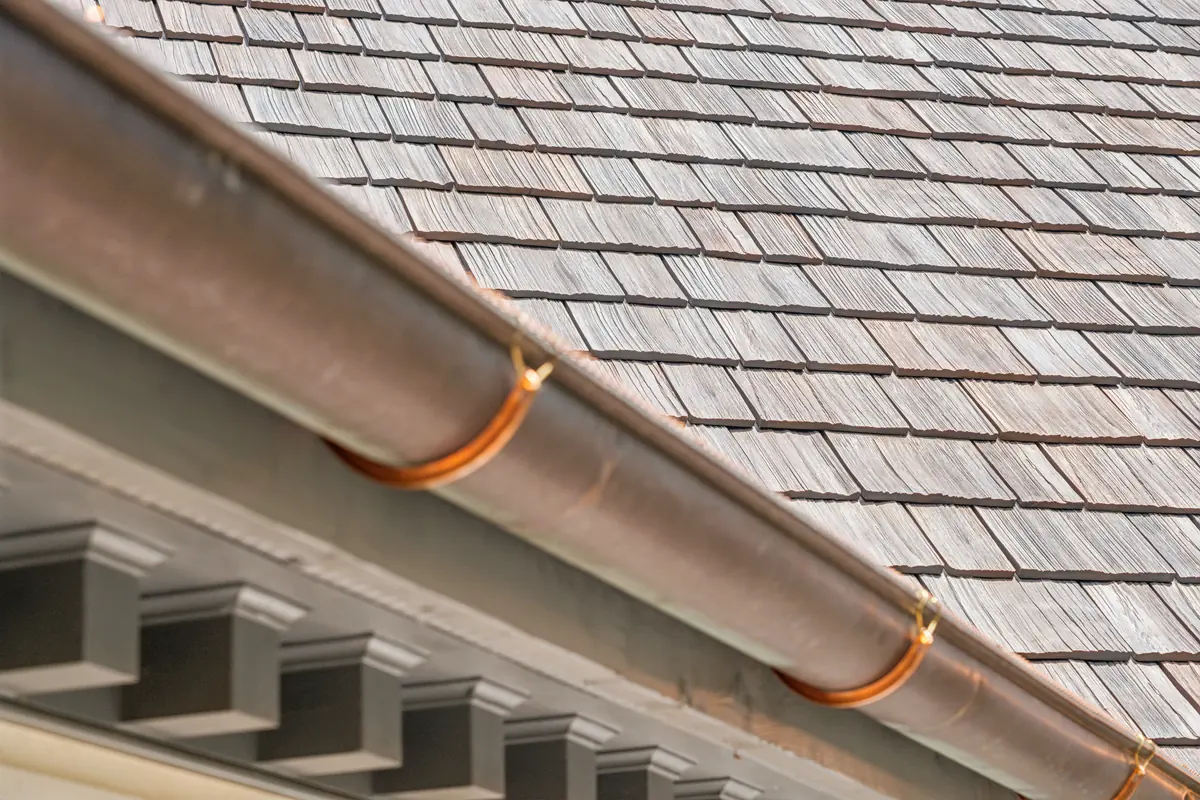 Brava composite cedar shake coursing above a copper half-round gutter