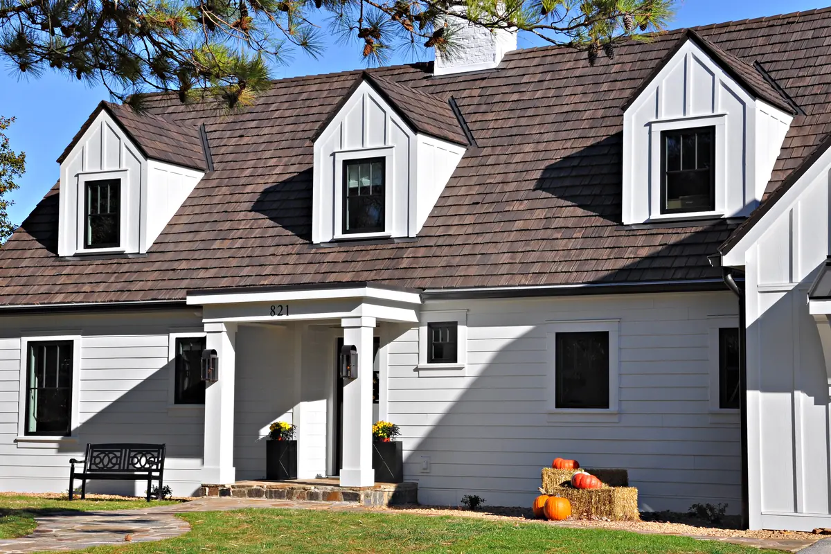 Brava composite cedar shake roof on a white cottage-style home with gabled dormers