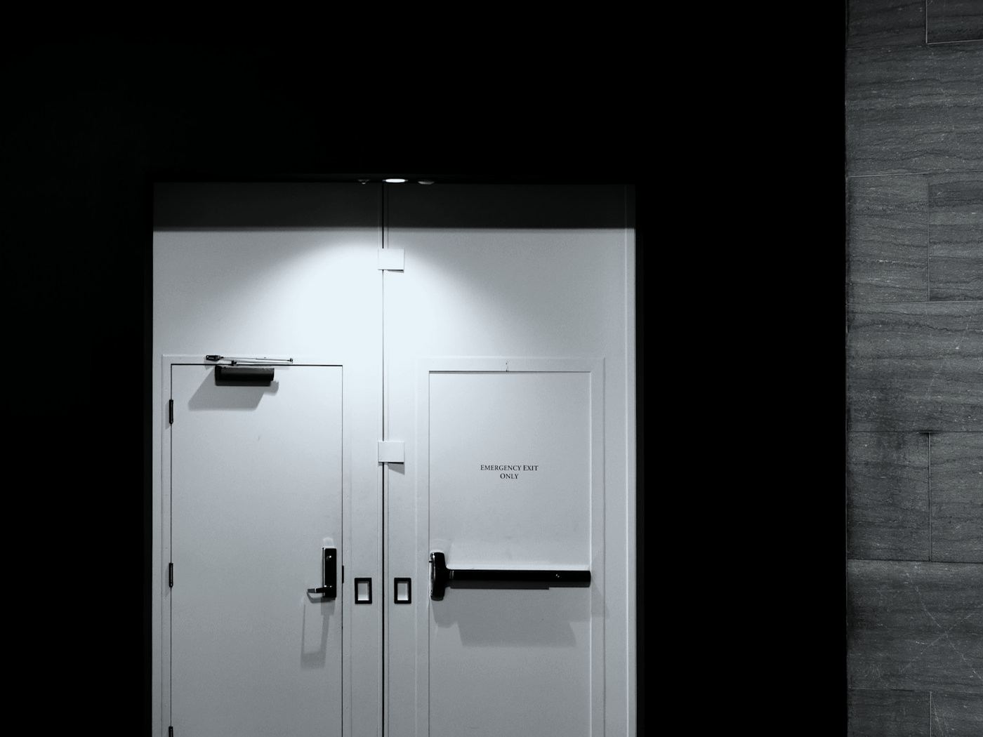 Pair of white commercial doors with a closer and panic hardware