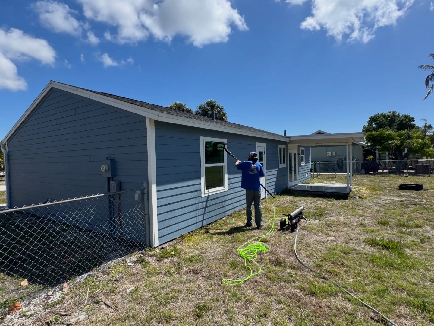 A B&B Exterior Services team member detail-cleaning windows during a soft wash on a Southwest Florida home