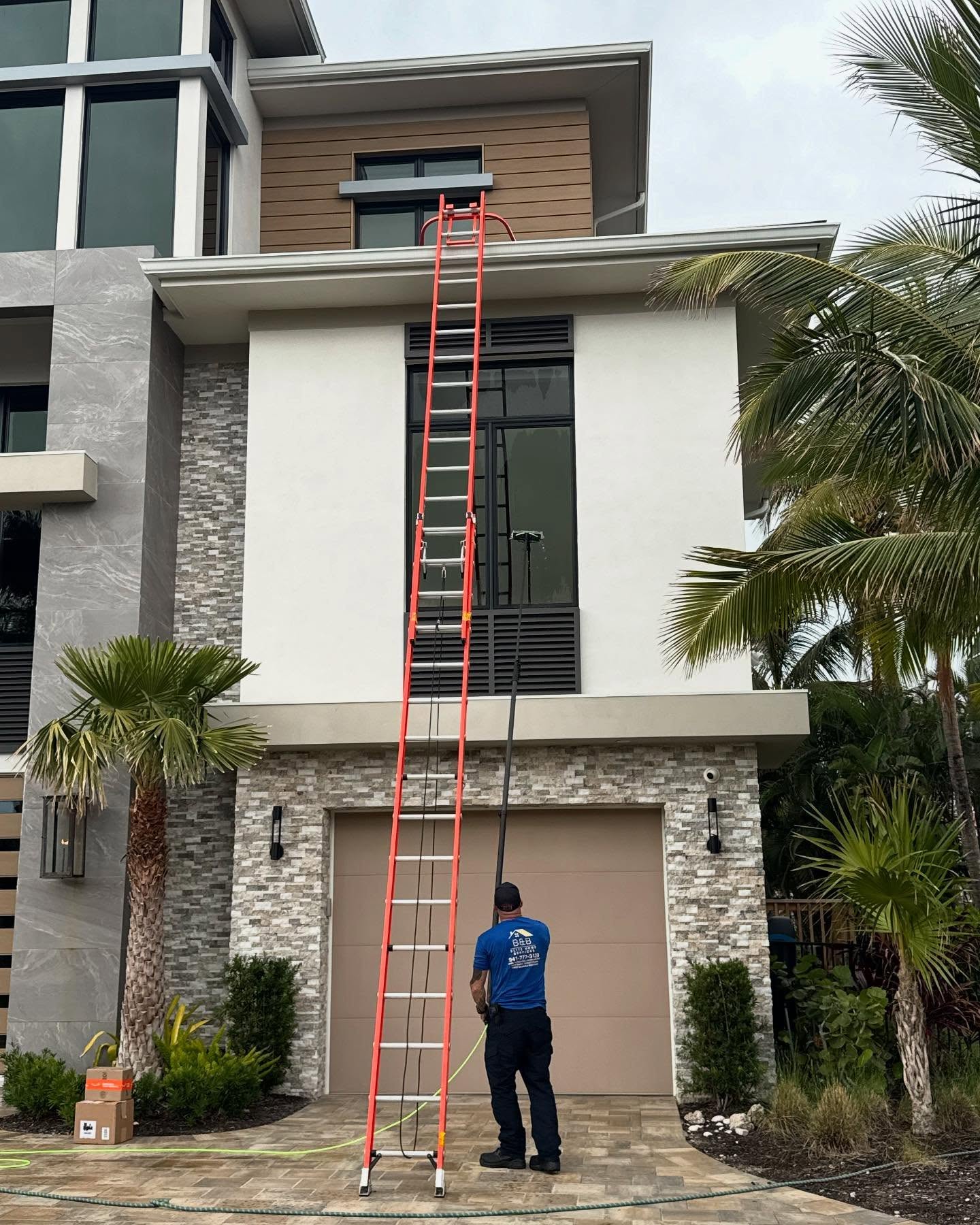 B&B roof washing from a ladder on a Southwest Florida home