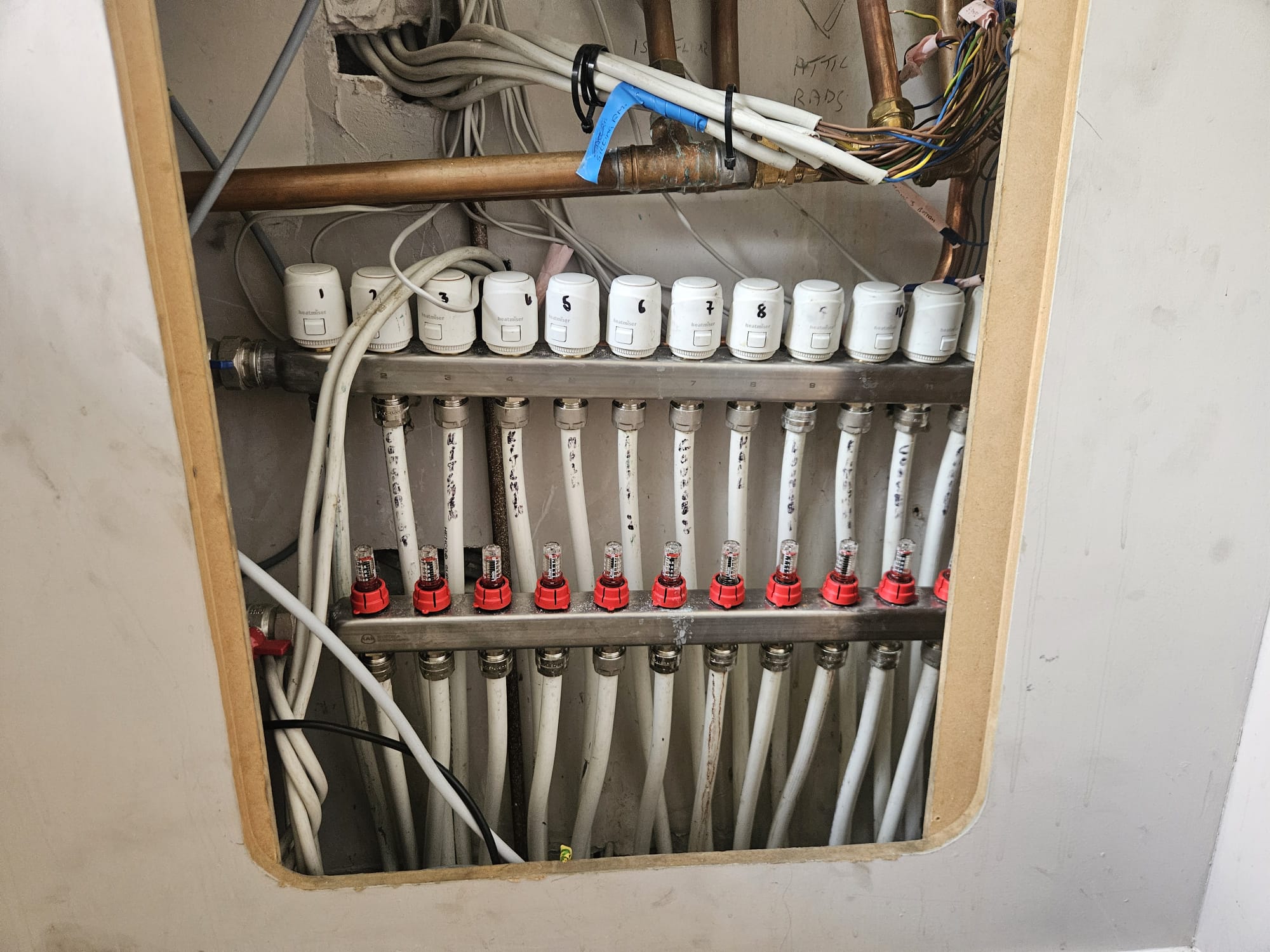 The upgraded heating manifold in Gerry's home, with a numbered actuator and a flow meter on every circuit