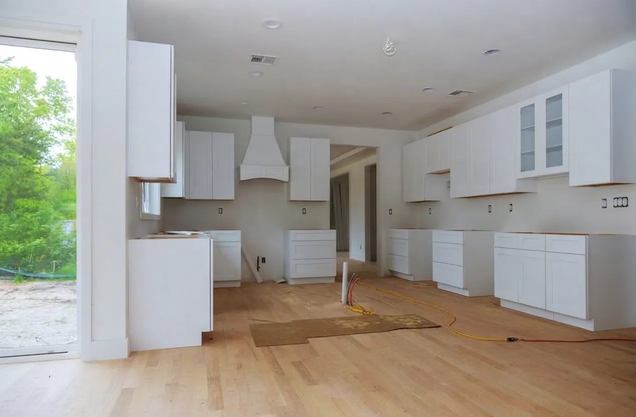 Modern kitchen renovation in progress featuring white shaker cabinets, wood flooring, and an open-concept layout.