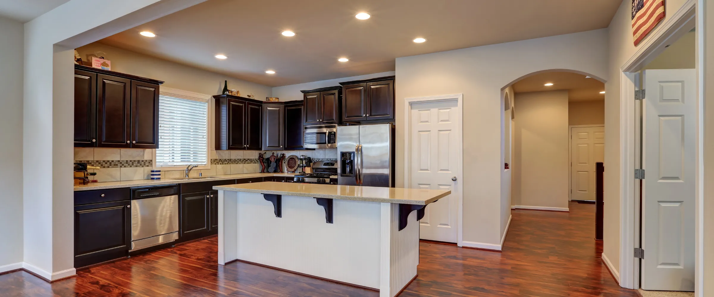 A modern kitchen with dark wood cabinets, stainless steel appliances, light countertops, and a central island. A modern kitchen with dark wood cabinets, stainless steel appliances, light countertops, and a central island.