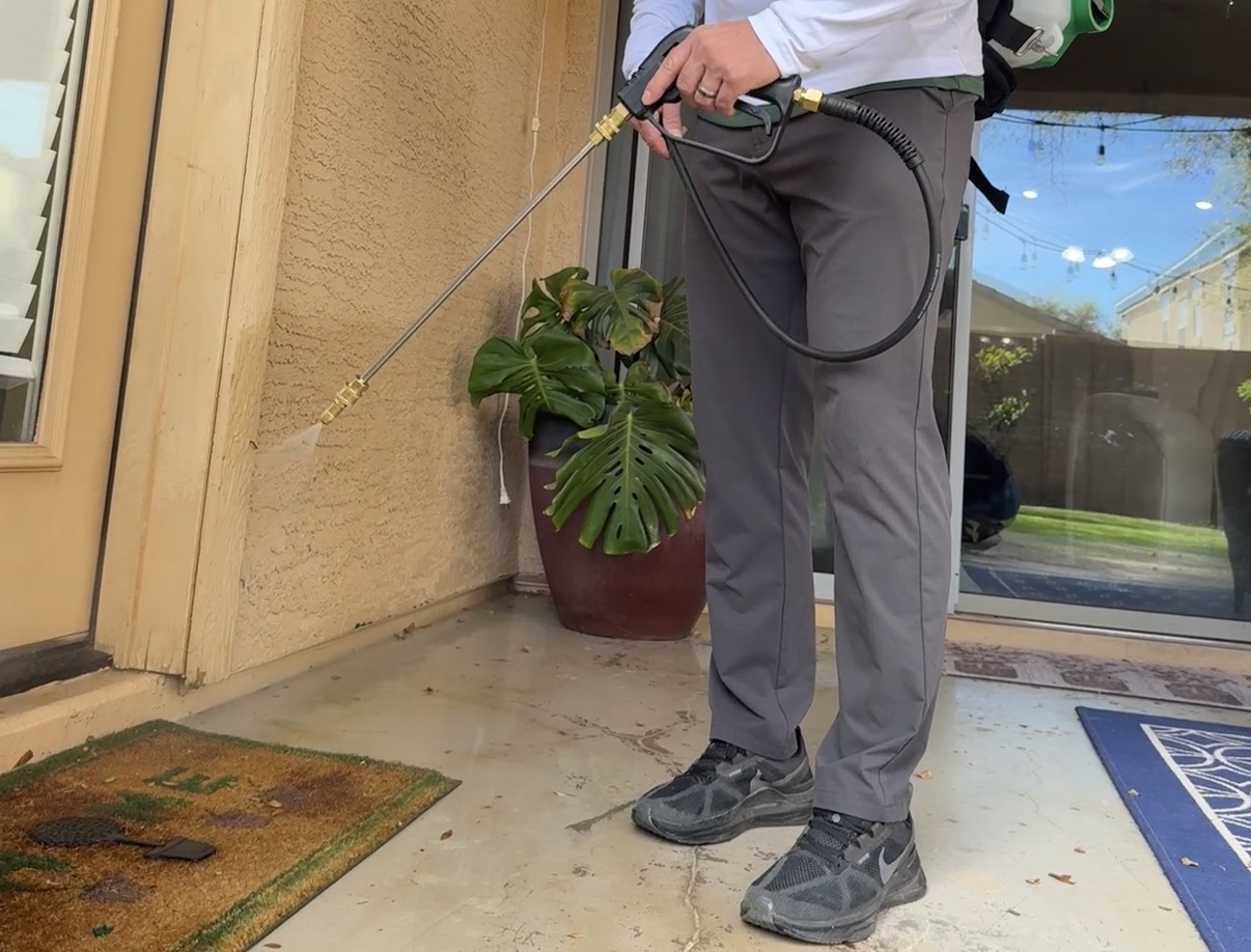 Gold Palm Pest Control technician applying a clean exterior foundation spray treatment in Arizona