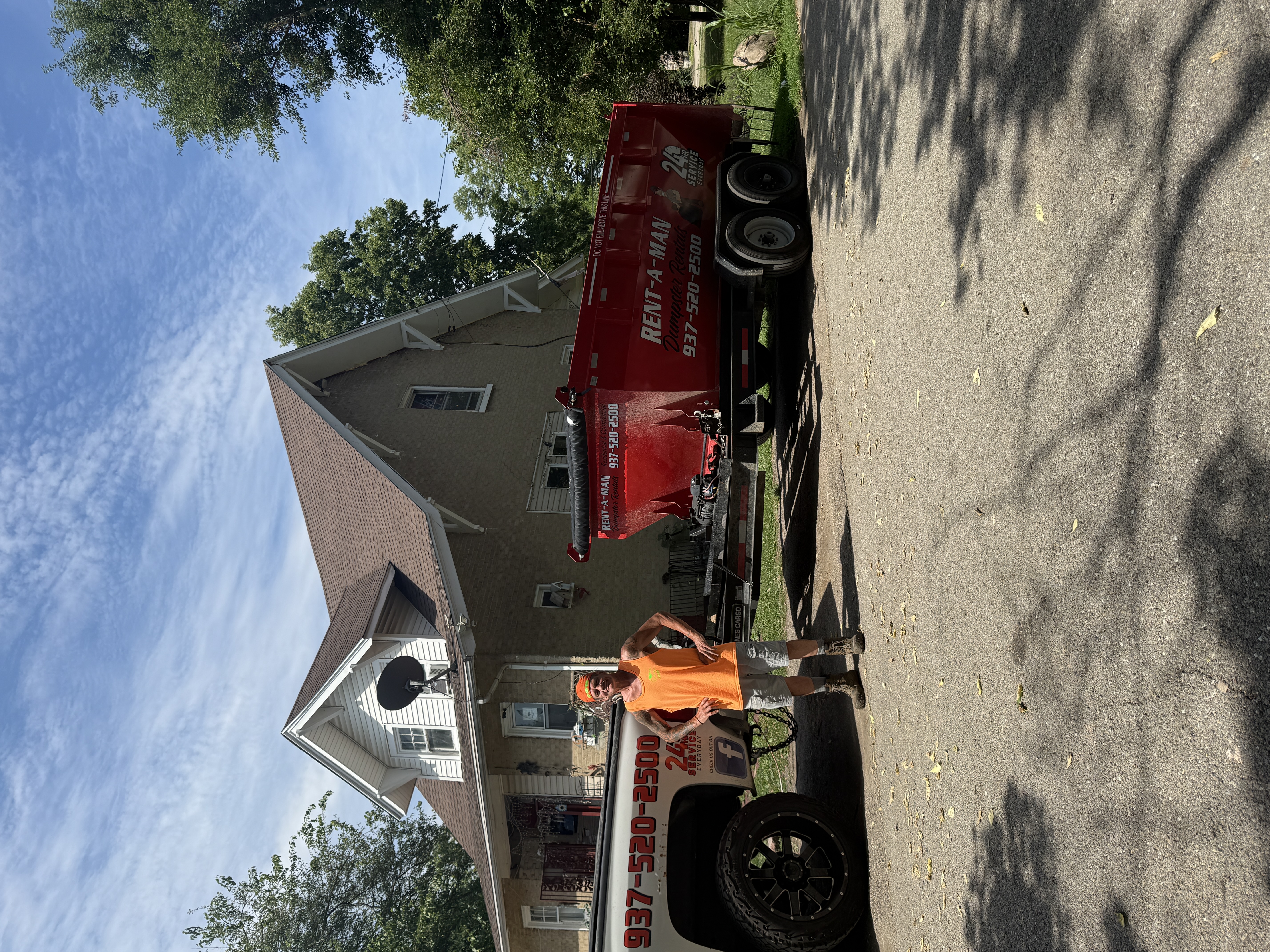 Rent-A-Man owner with his truck and loaded red dumpster trailer outside a Dayton home