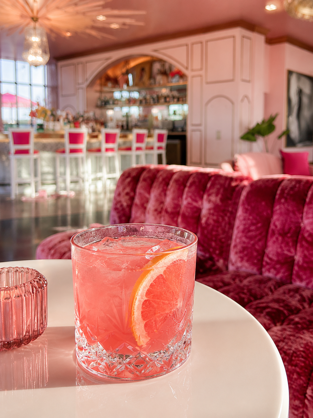 A pink grapefruit cocktail on the velvet bar banquette