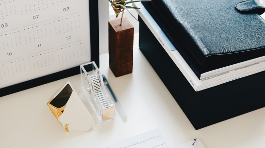 Clean white desk with planner and black notebook