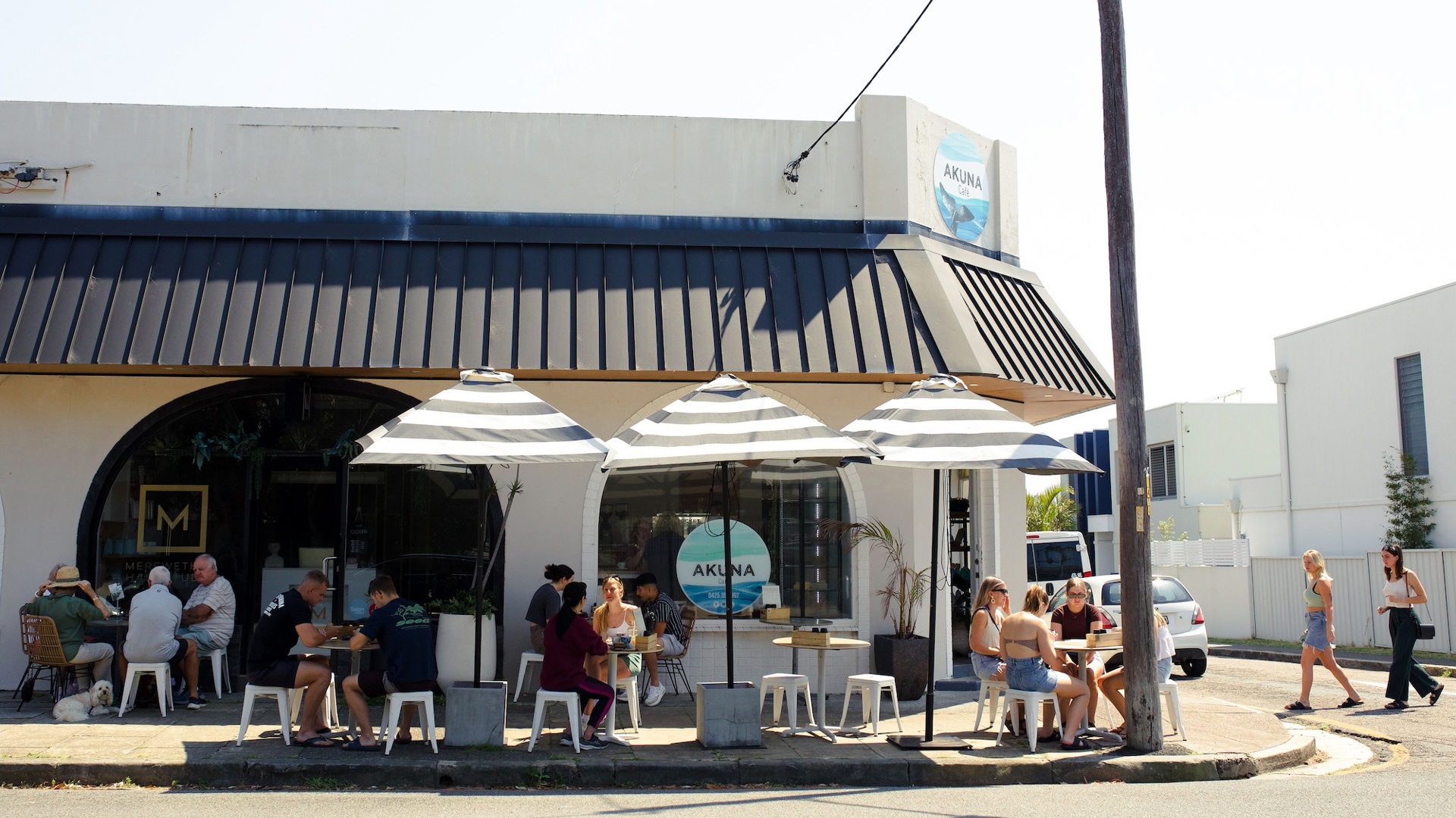 Akuna Cafe Merewether — the corner, striped umbrellas and full sidewalk tables