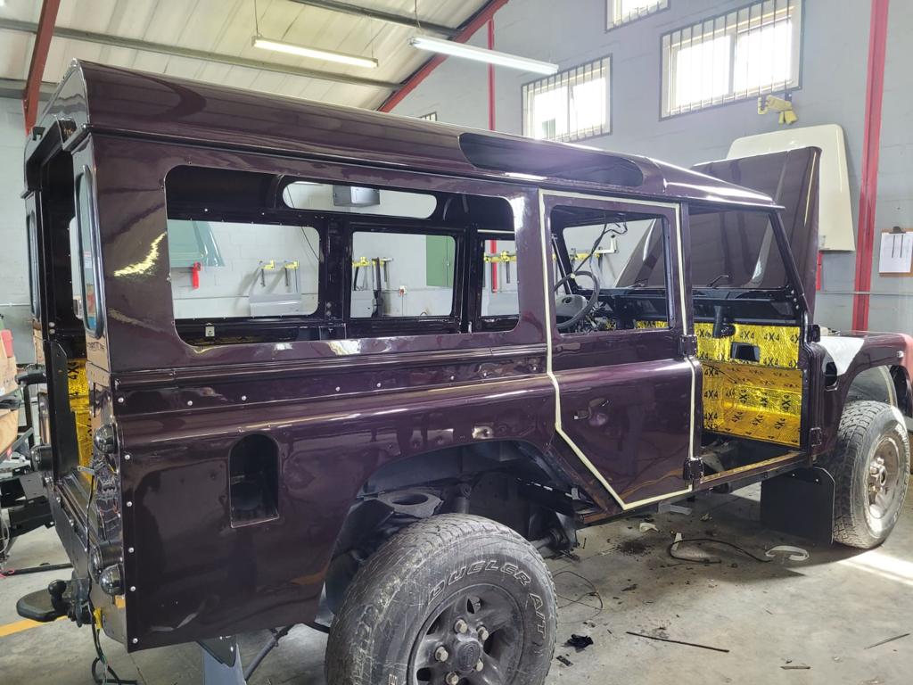 A partially assembled Land Rover Defender suv in a workshop, undergoing restoration or customization.