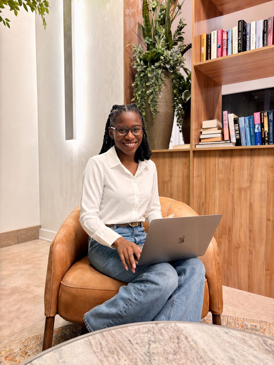 Wildiah Edouard, founder of Grow and Thrive, working on her laptop in a lounge chair