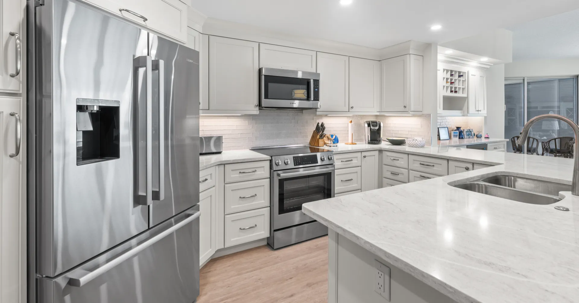 White kitchen with marble-look countertops, white shaker cabinets, and stainless appliances