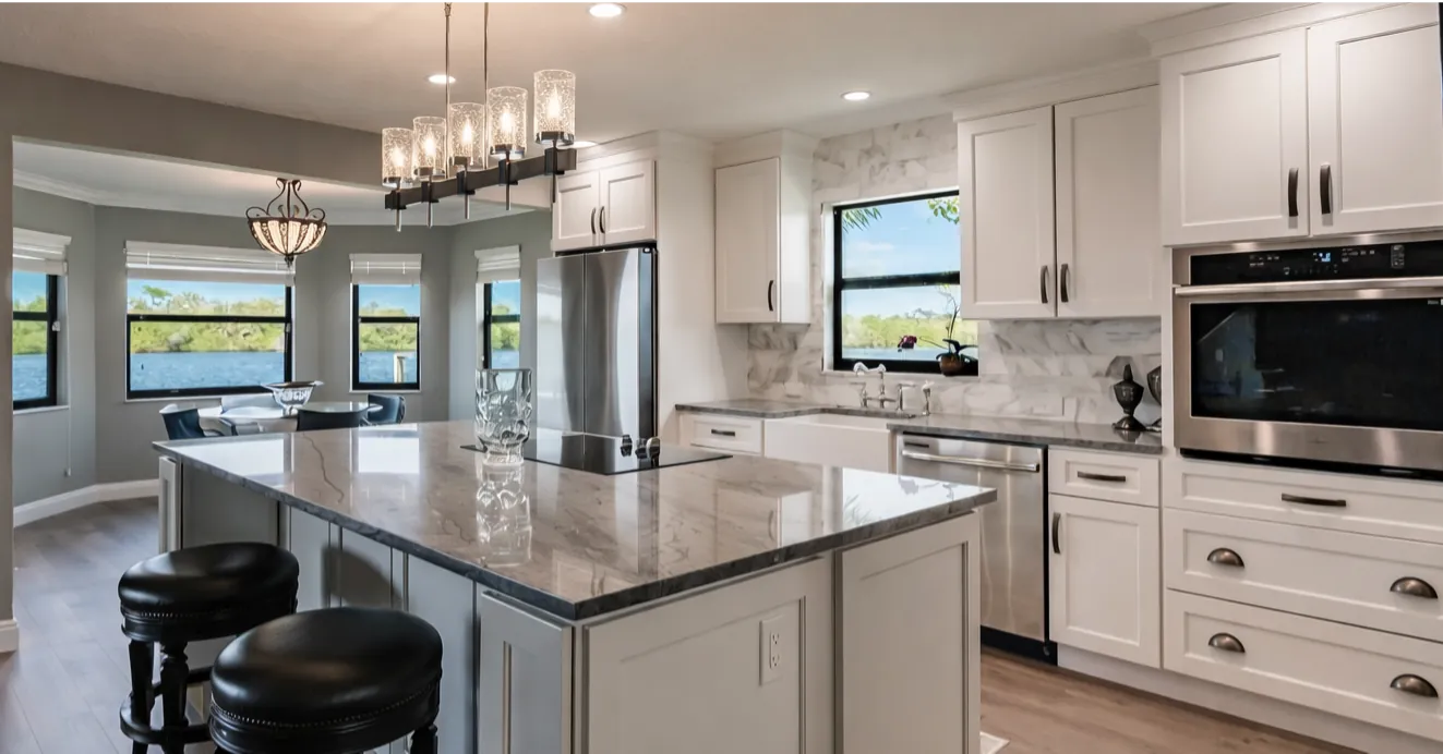 Kitchen remodel with white shaker cabinets, gray stone island, and glass pendant lighting