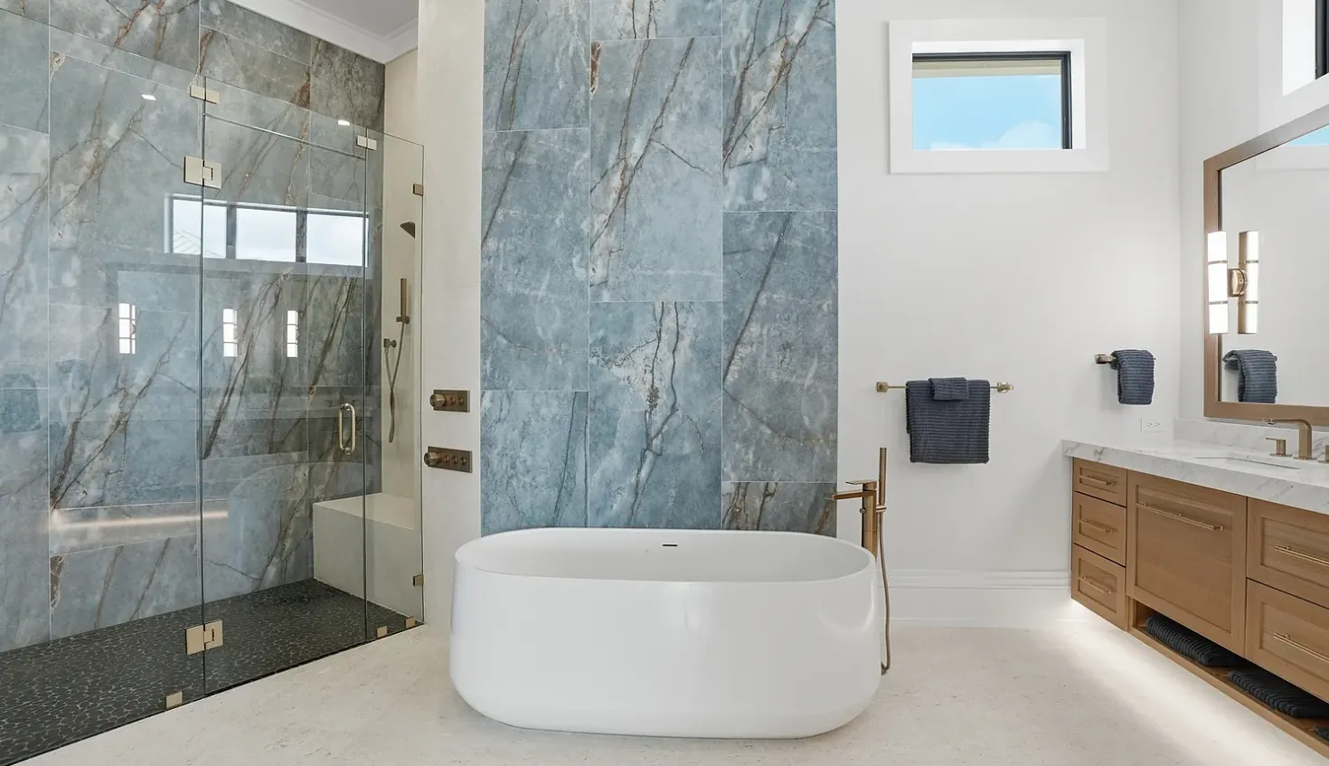 Primary bathroom with blue marble-look shower wall, freestanding tub, and floating oak vanity