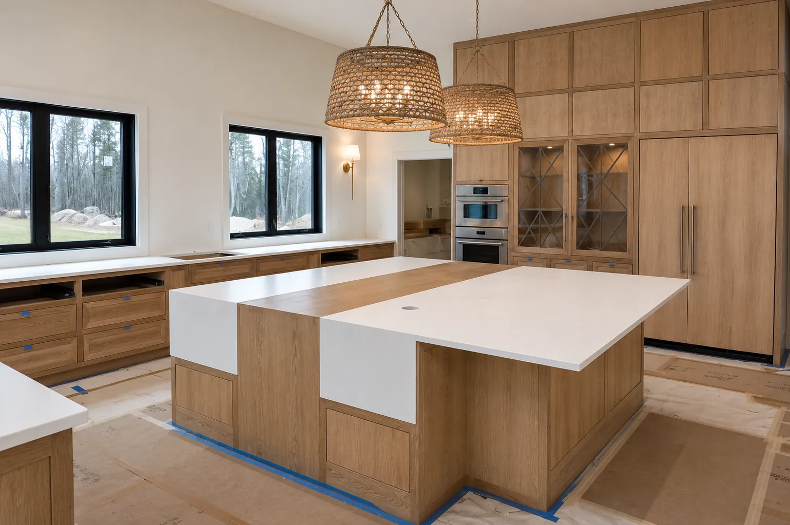 Kitchen cabinetry install in progress: white oak cabinets, two-tone island, and woven pendants