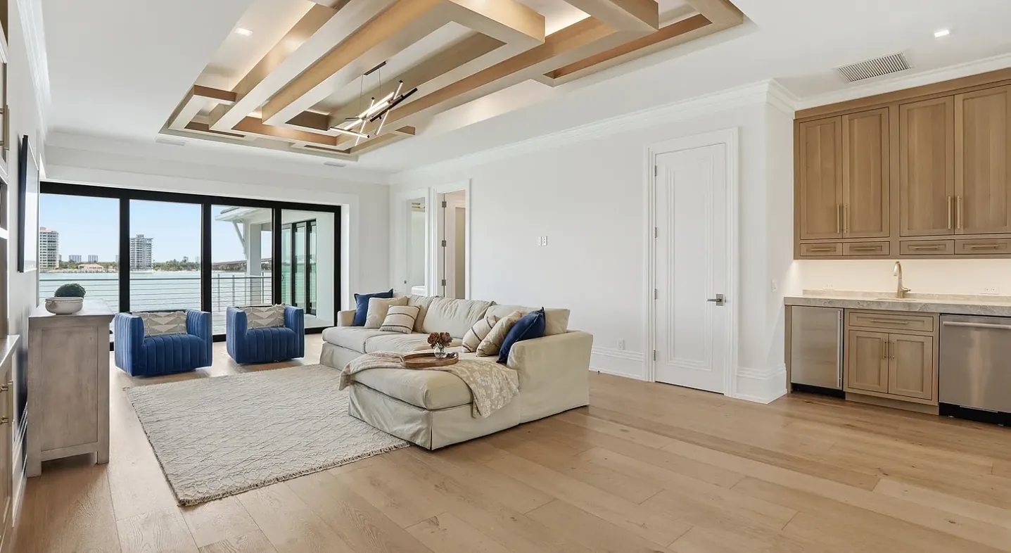 Great room with wide-plank oak floors, wood-beam ceiling detail, and oak wet bar cabinetry