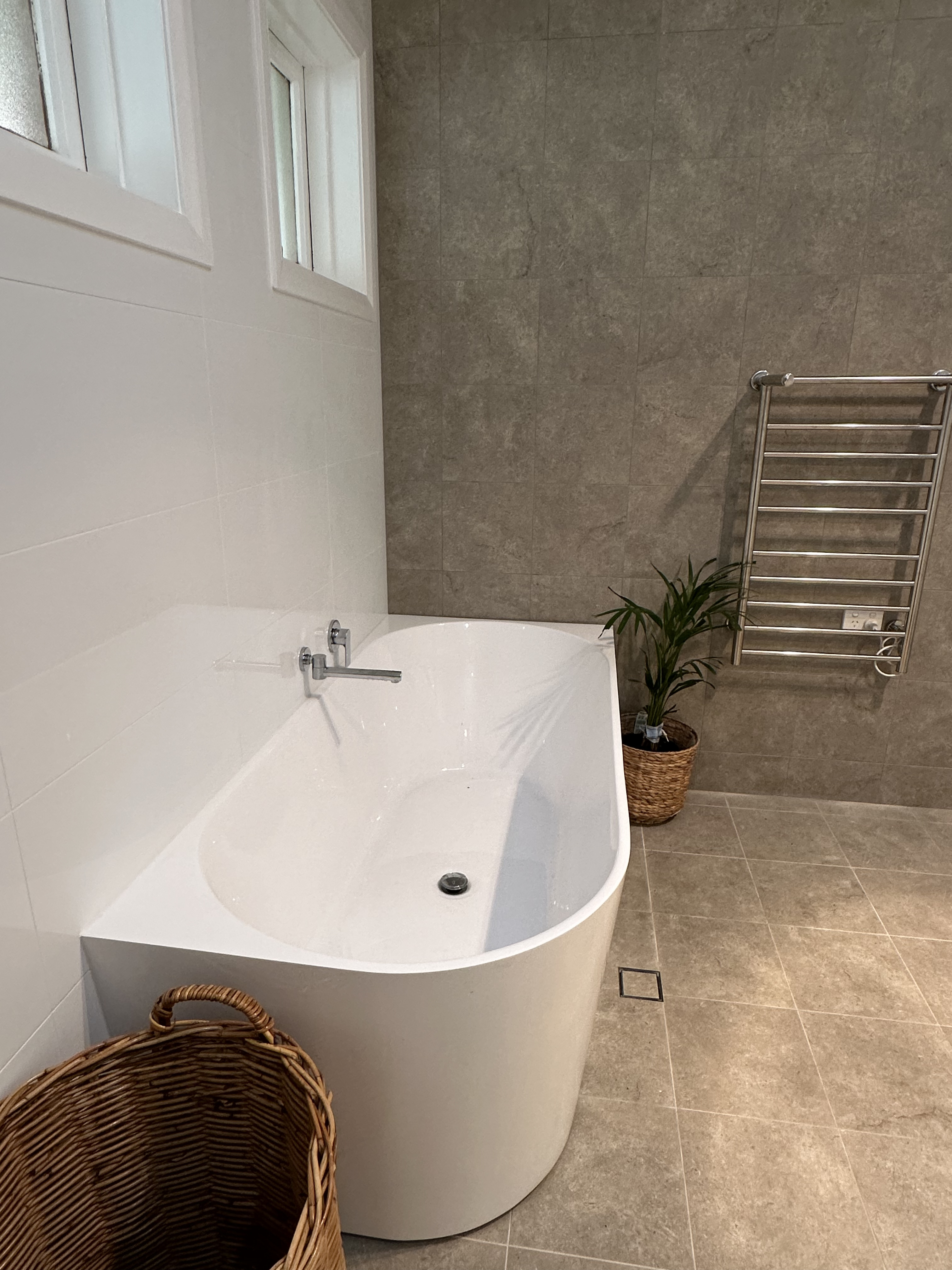Finished bathroom with freestanding bath, heated towel rail and large grey wall tiles in Dubbo
