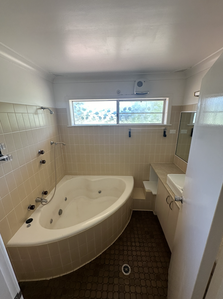 Main view of the renovated bathroom with corner spa bath and marble tiles in Trangie