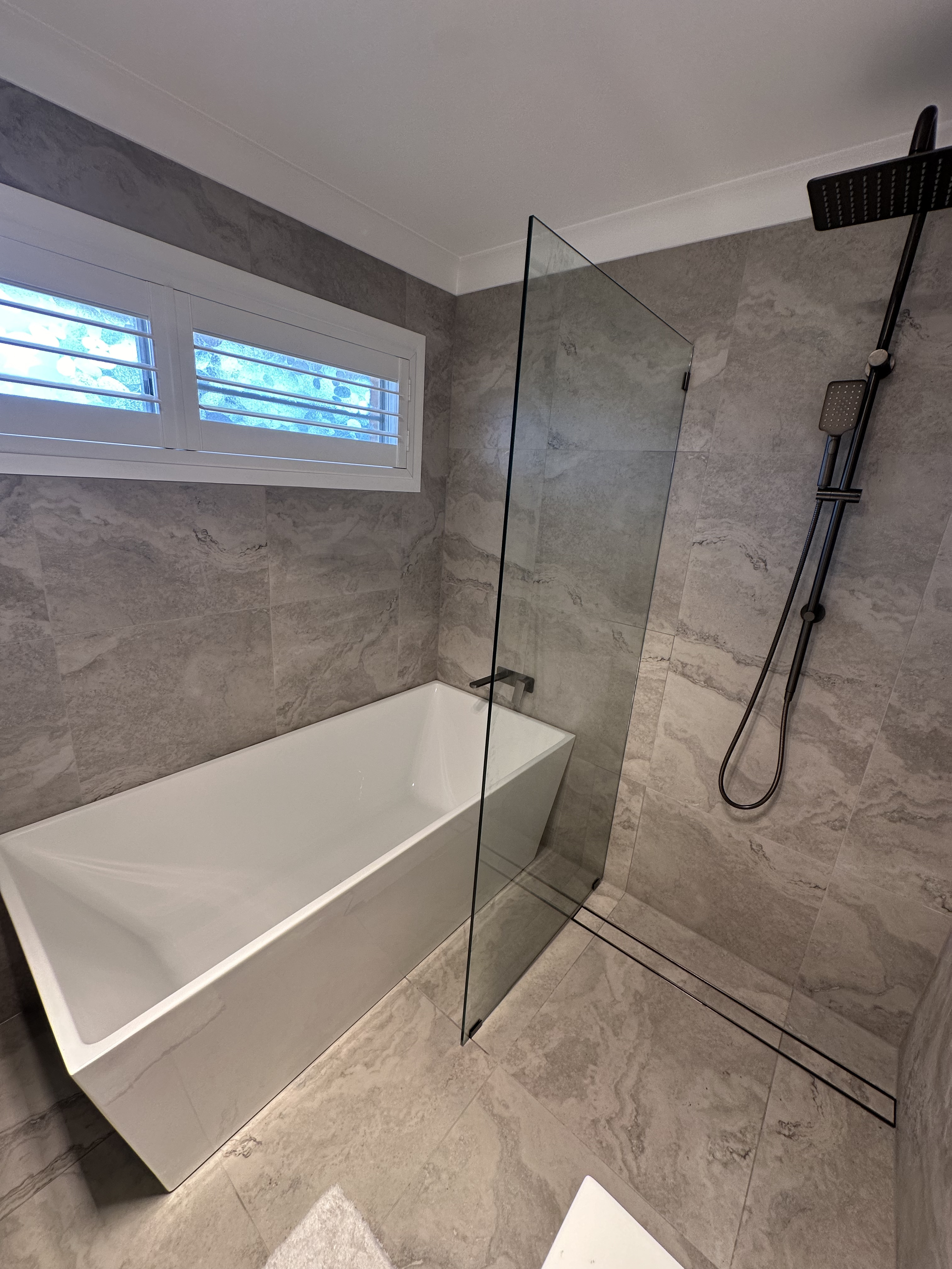 Finished bathroom with corner spa bath, rainfall shower and marble-look tiles in Trangie