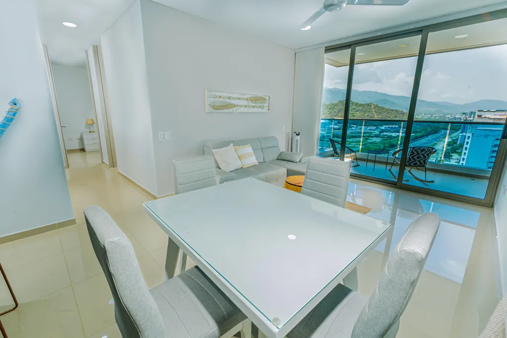 Comedor con mesa de vidrio y vista al balcón y el mar