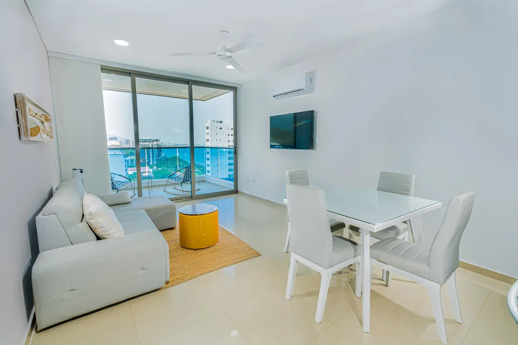 Sala de estar amplia con sofá, comedor y balcón con vista al mar