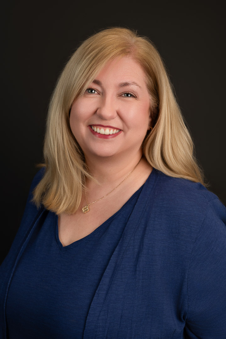 headshot of a professional blond woman in a blue cardigan