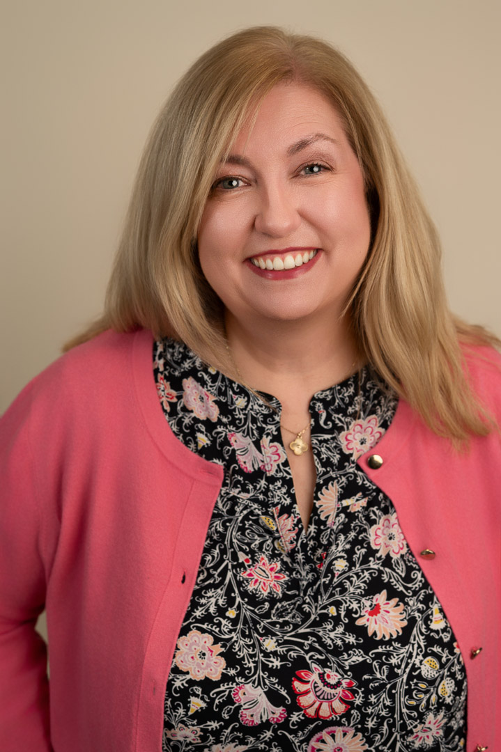 headshot of a blonde woman in a hot pink cardigan