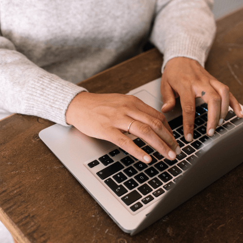 Hands of a woman of color typing on a laptop