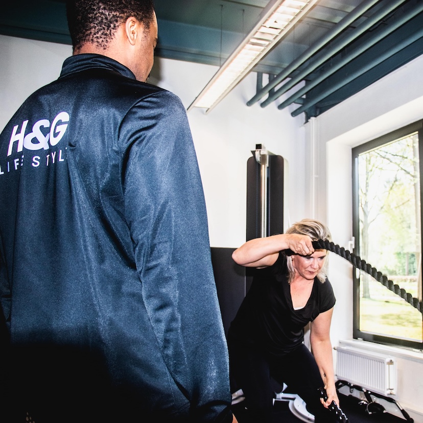 Personal trainer helpt met bankdrukken
