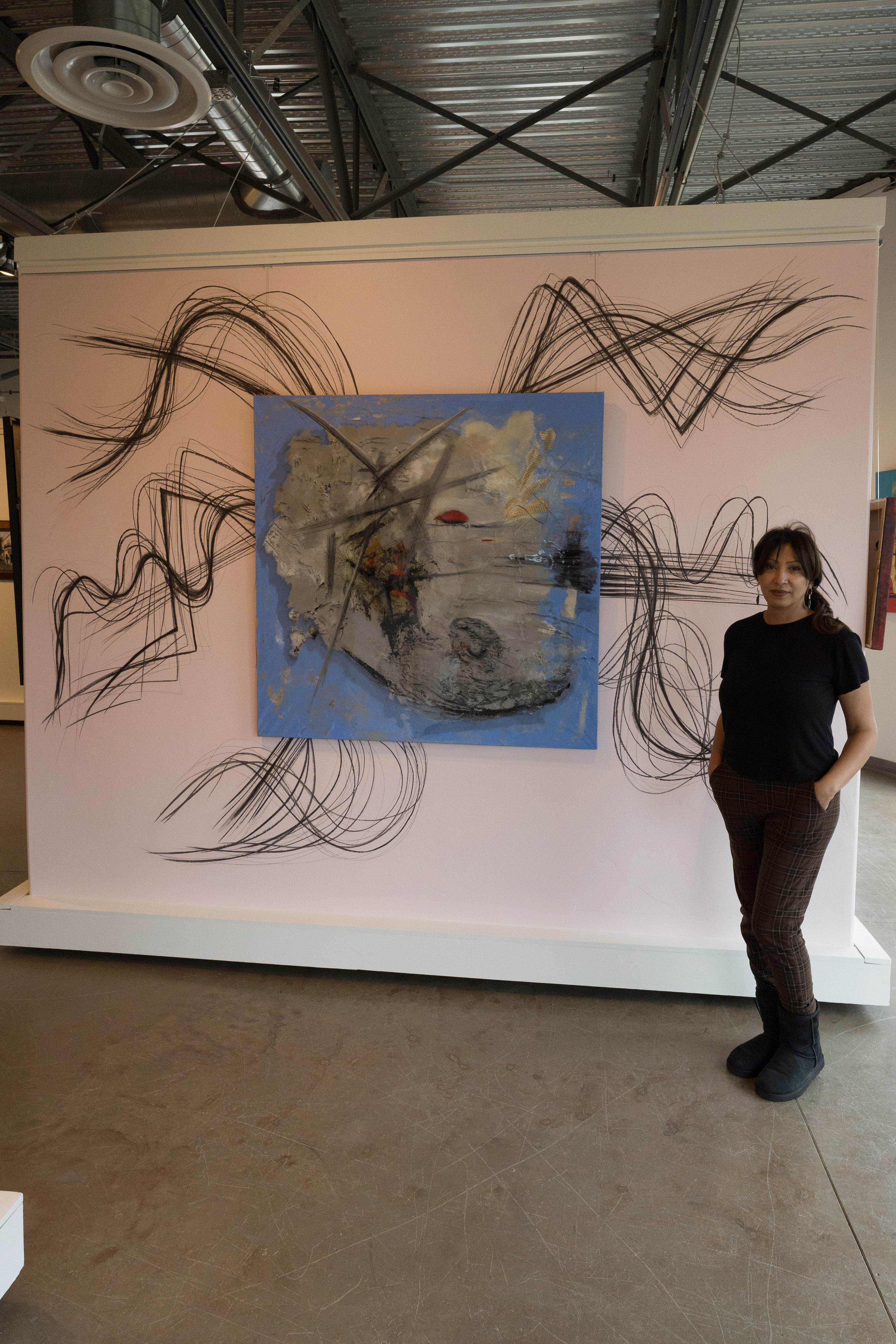 Woman standing beside a large mixed-media abstract painting installed on pink gallery walls during the Bold Women, Soft Walls exhibition at Create Gallery and Frames in Garden City, Idaho.