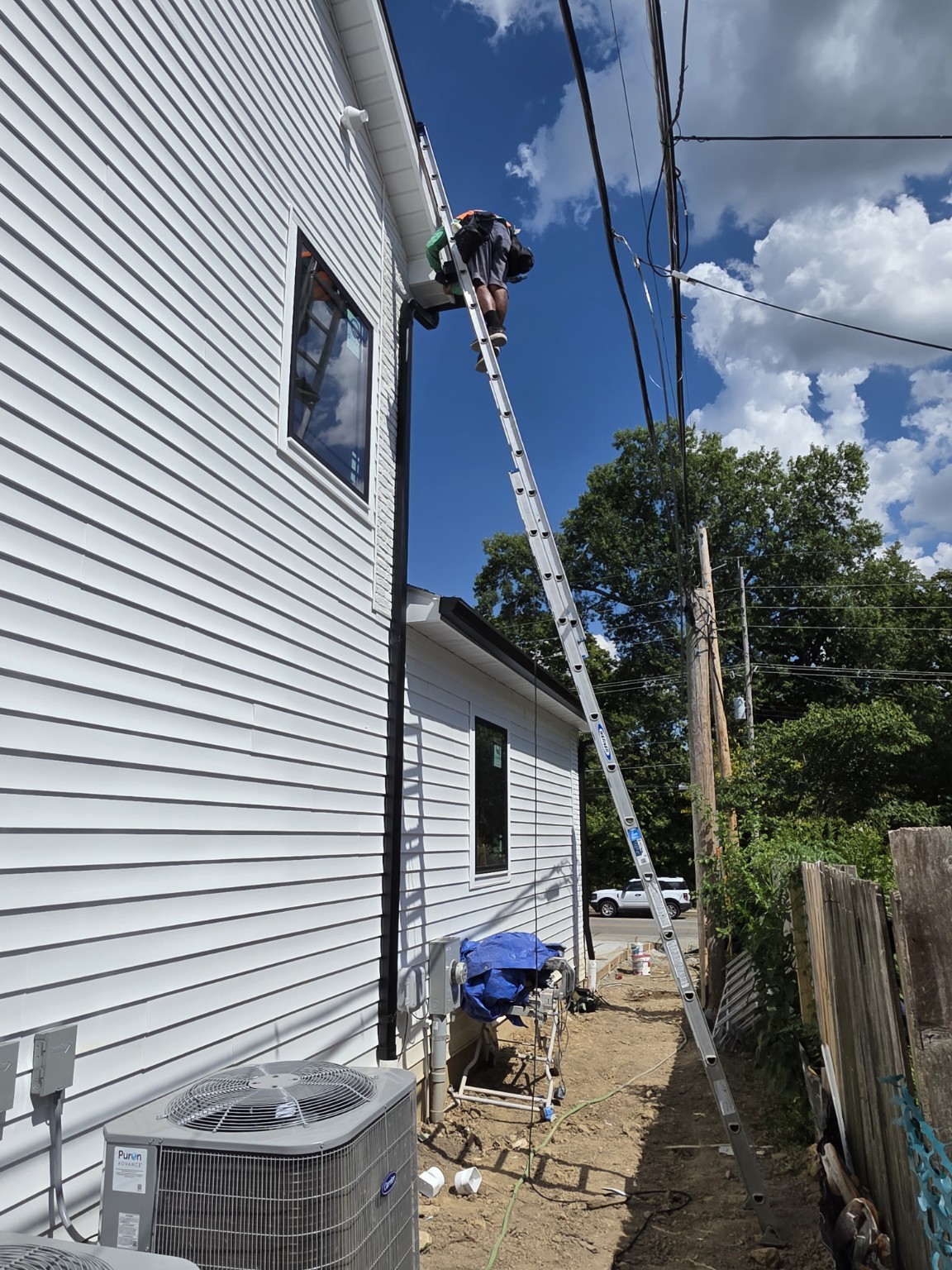 SuperRoofer installer securing a gutter system from a ladder