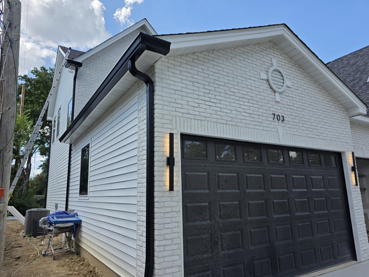 Close-up of a black gutter and downspout installed on white brick