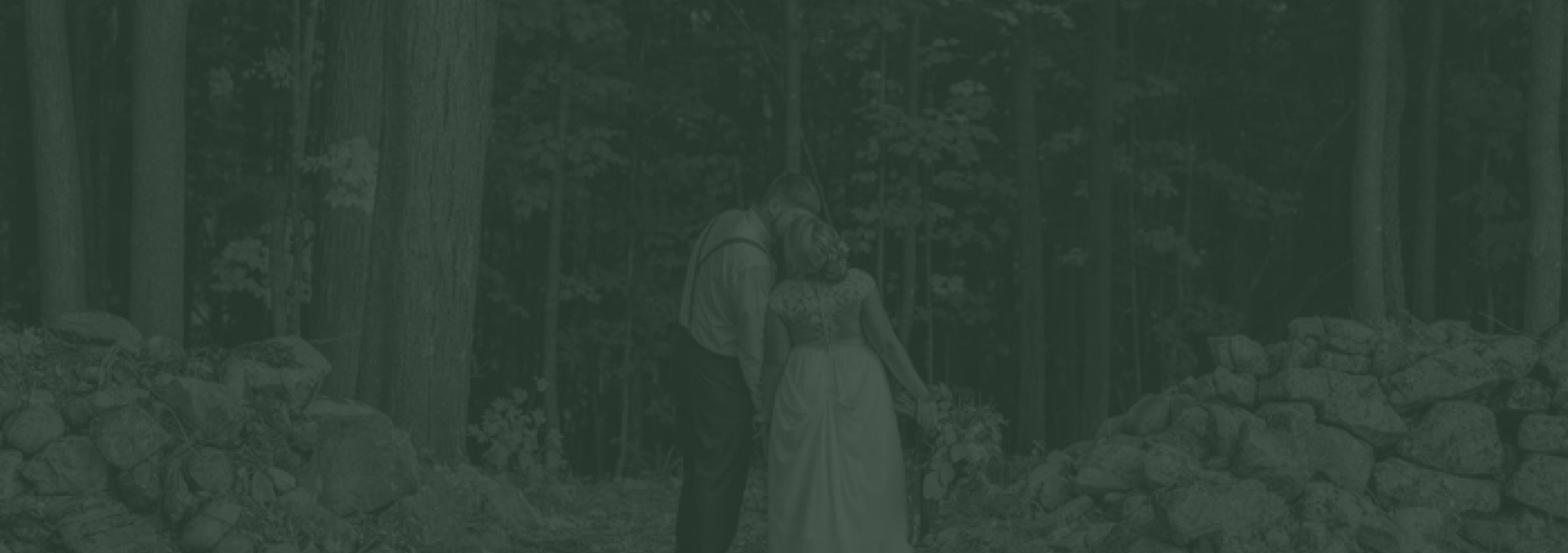 A couple among the trees and old stone walls on the property