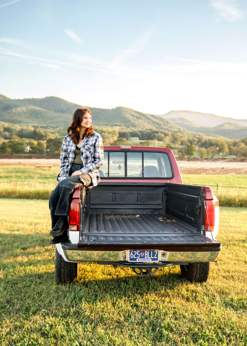 An expecting couple in green and brown snuggle holding hands under the bump in a park in the fall captured by their Johnson City maternity photographer.