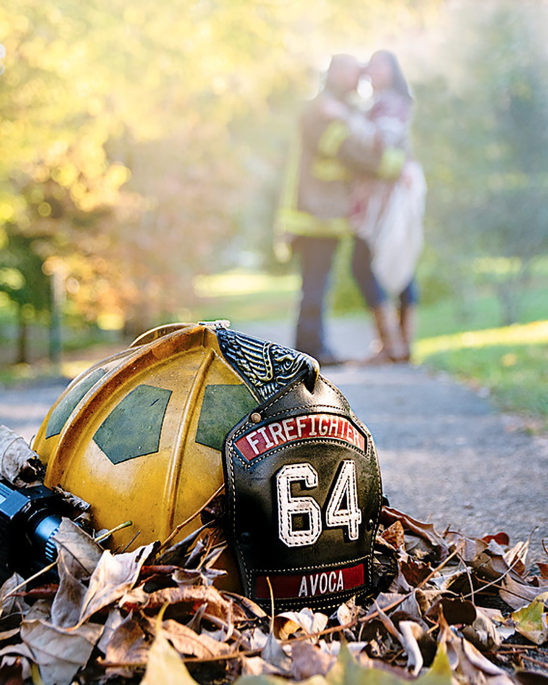 Couple stands in the background with a firefighter hat in the foreground at a engagement session near Johnson City, TN.