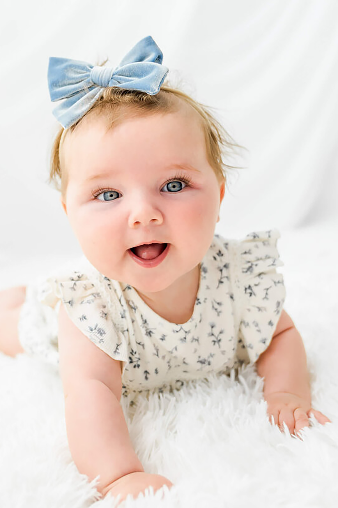 A new dad in a white polo cradles her sleeping newborn against his chest in a white onesie.