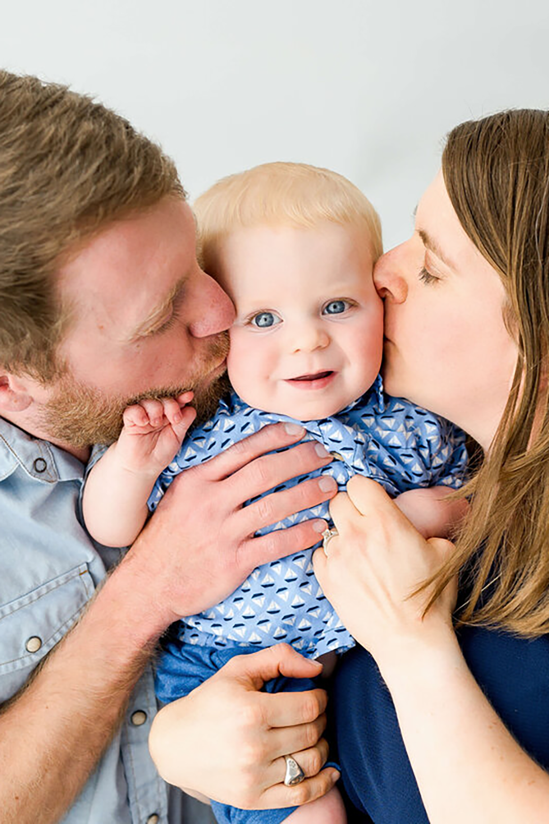 A baby sleeps under a cozy blanket on her back with a large headband.