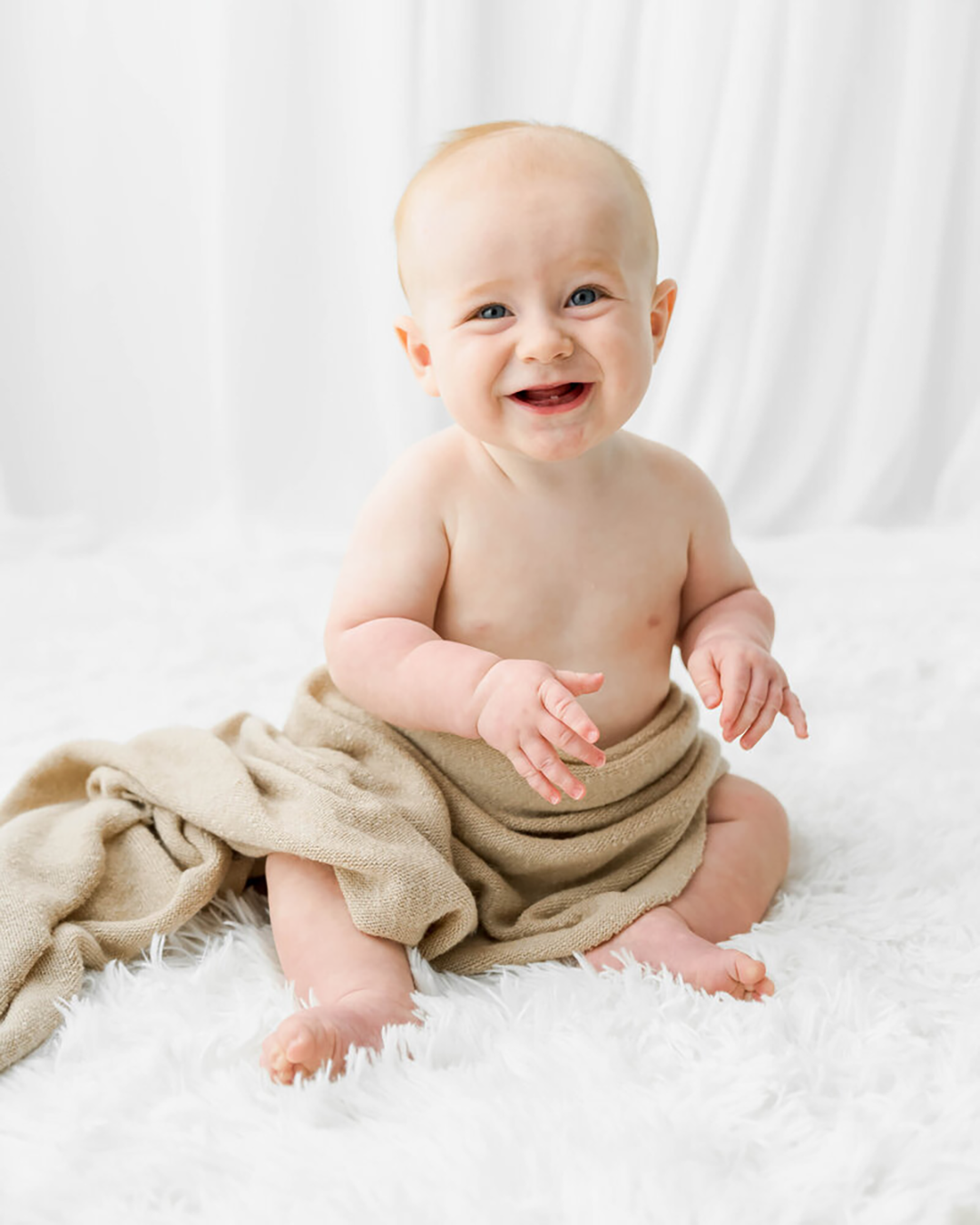 A baby smiles while wrapped in a tan wrapin Johnson City.