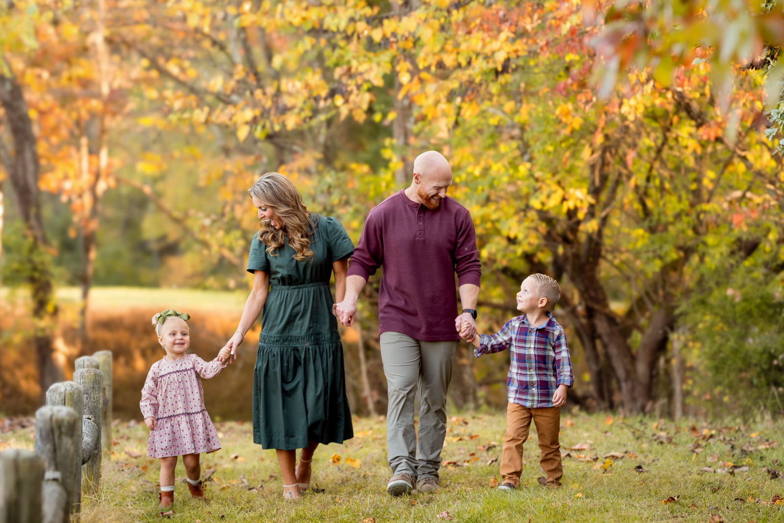 A family of four smiles together during an autumn portrait session.